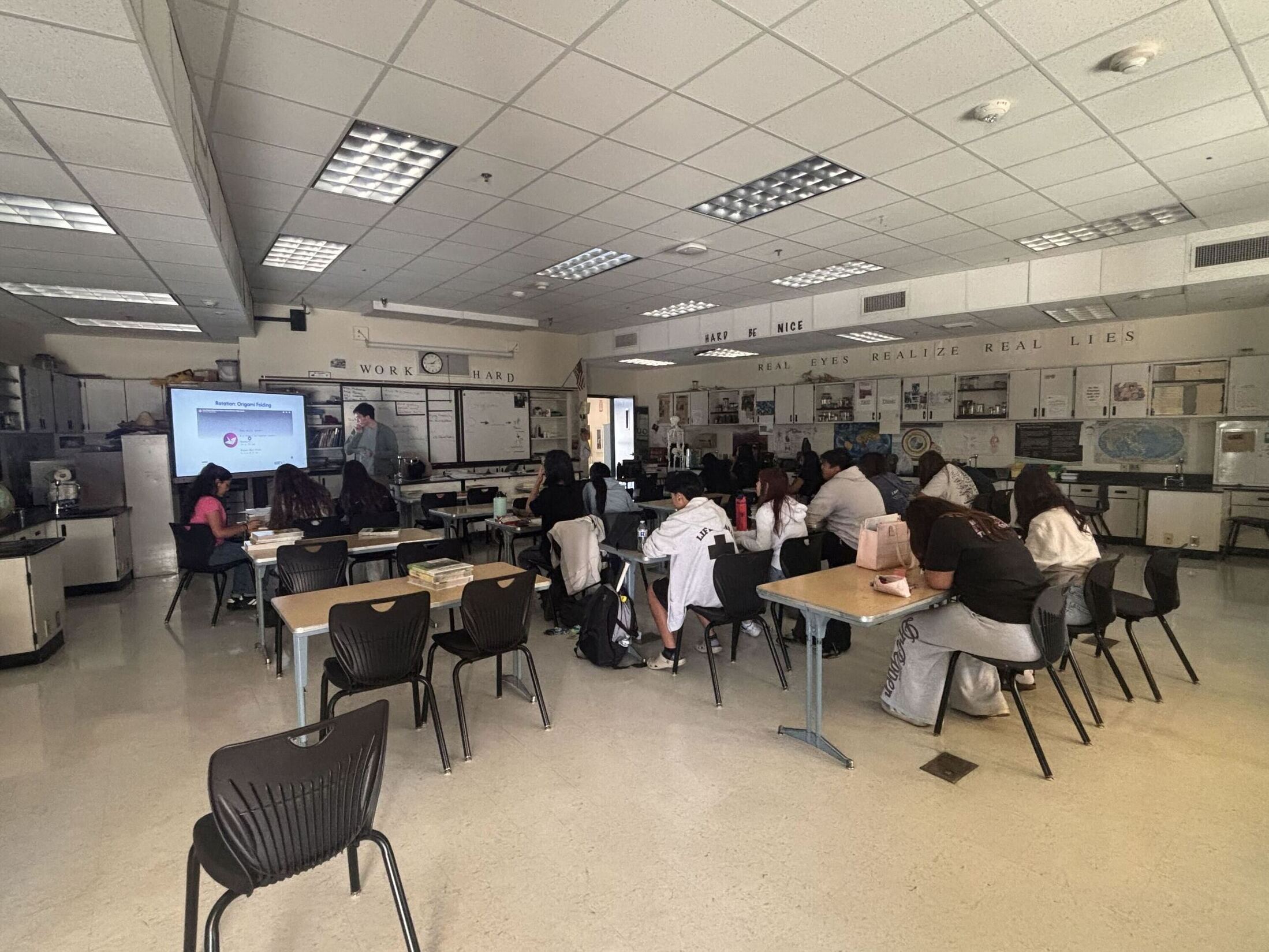 Classroom filled with students. All of them have their heads down.